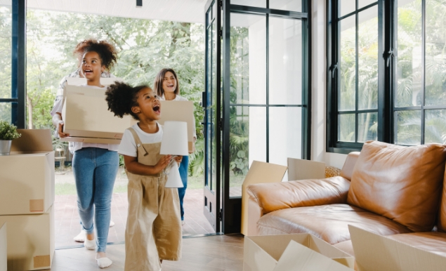 Mother and her two daughters moving boxes into their new home.